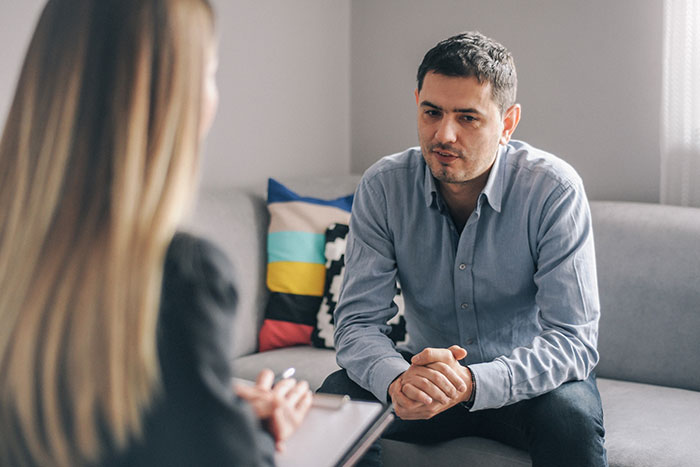 Man sits on couch talking to therapist