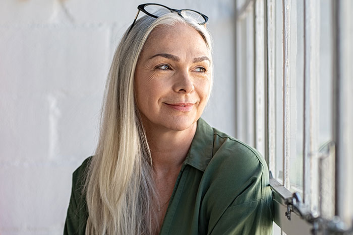 Woman with long gray hair and glasses on top of head