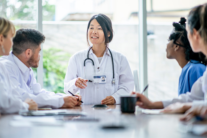 Doctor speaks with trainees at conference table