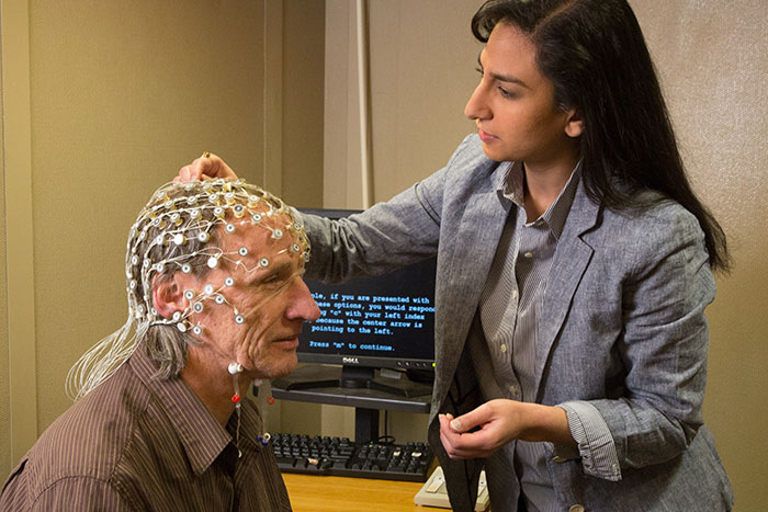 Researcher helps a volunteer into a EEG rig