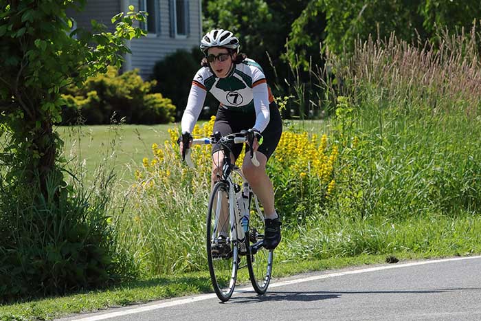 Cyclist on the road, lush wildflowers by side of road