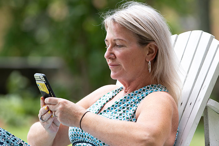 Woman sits and looks at smartphone