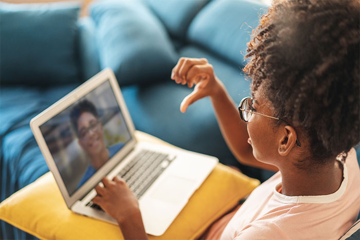 Young girl talks to teacher via computer