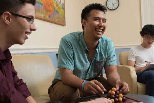 Teen boys laugh and play in common room at 3East DBT program for adolescents and young adults
