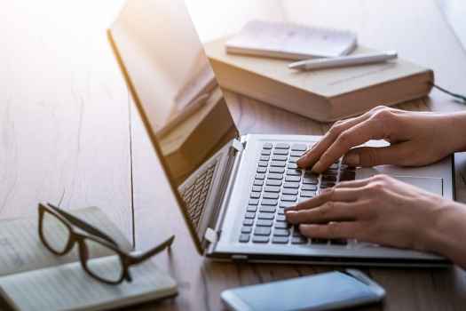 Hands typing on laptop
