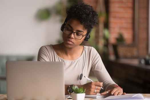 Young woman watches webinar taking notes