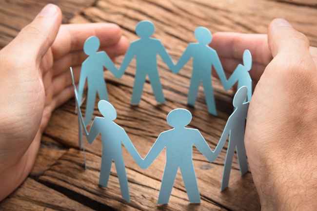 Hands encircle a ring of blue paperdolls