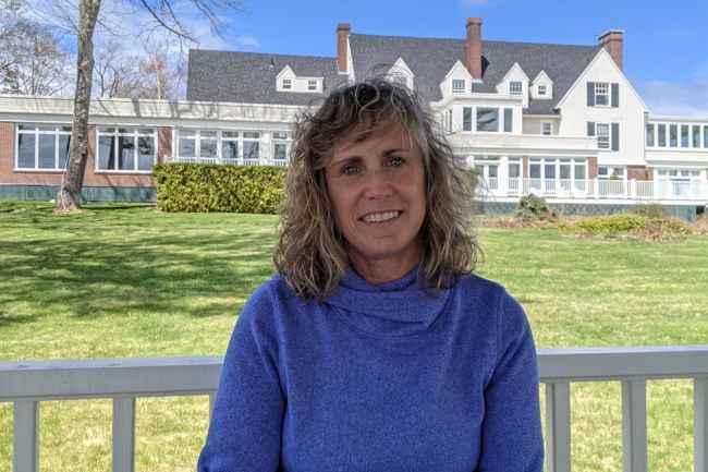 Woman outside large home on sunny day