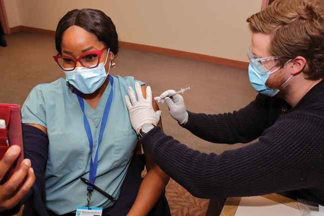 Woman taking selfie while man delivers vaccine