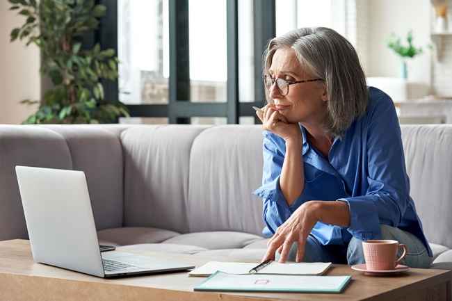 Woman on couch watches laptop screen