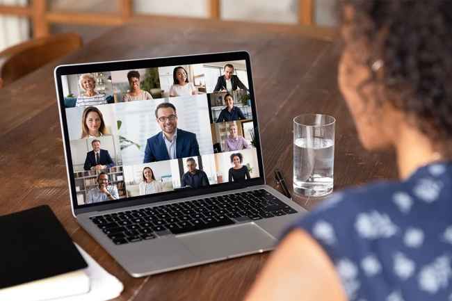 Woman looks at virtual meeting on laptop screen