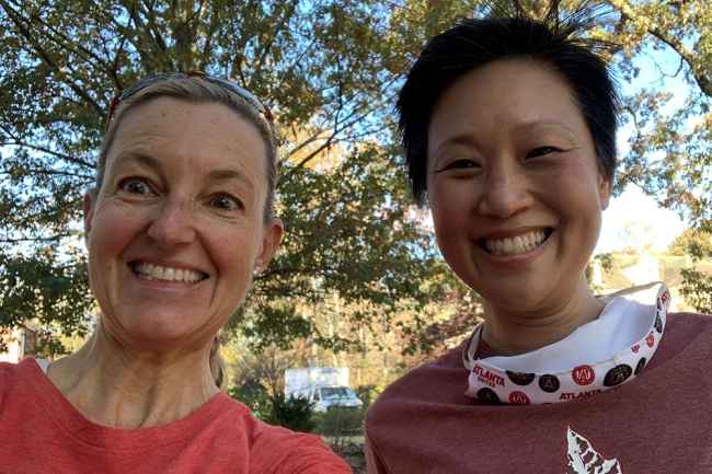 Two women pose for post run selfie by trees