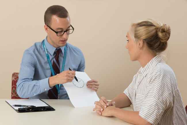 A clinician shows a patient how to take a neuropsychological test