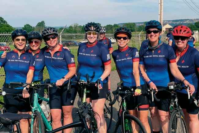 Bicyclists in blue shirts pose for picture
