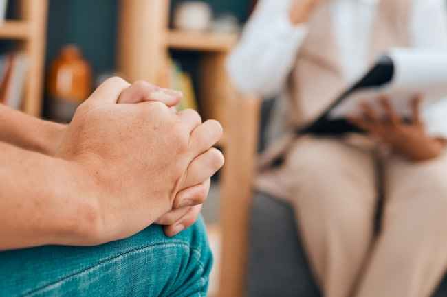 Person sitting in therapy session with hands clasped