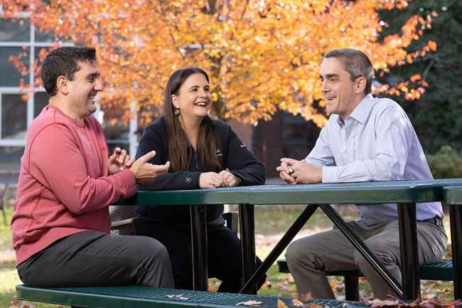 Group of people sitting and smiling at a table outside