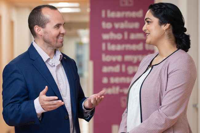Two staff person standing speaking with each other