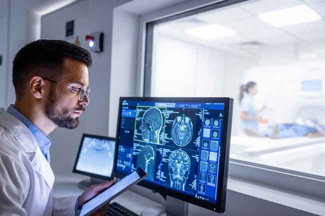 Man looks at computer showing brain scans