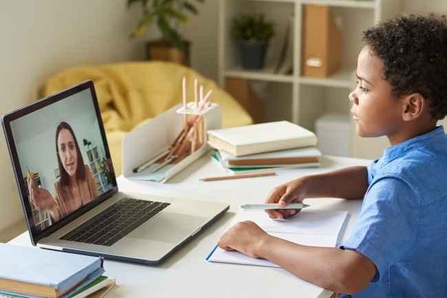 Boy sits at desk with a laptop