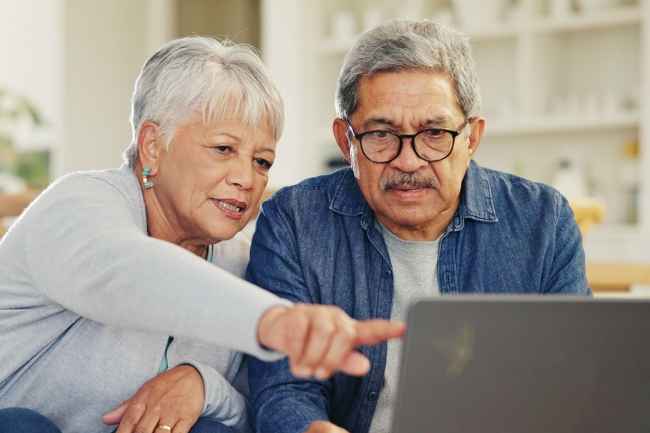 Senior couple at desk with laptop
