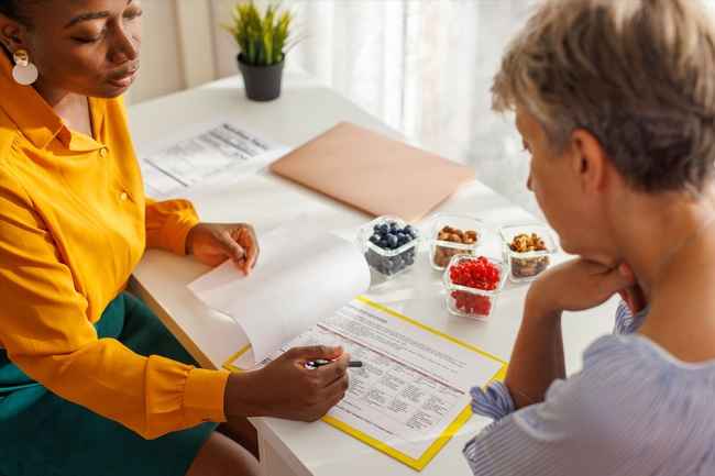 Female nutritionist discussing fruit portions with elder patient