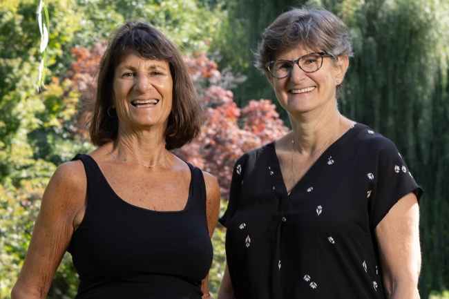 Two sisters in black shirts pose outside