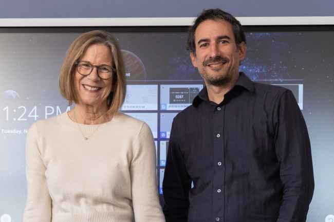 Two educators stand in front of smartboard