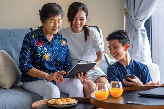 Multi generation family using digital tablet on sofa