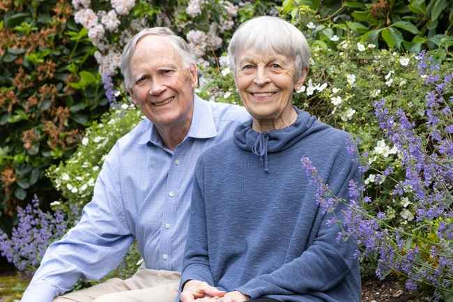 Two older adults sit outside in a garden
