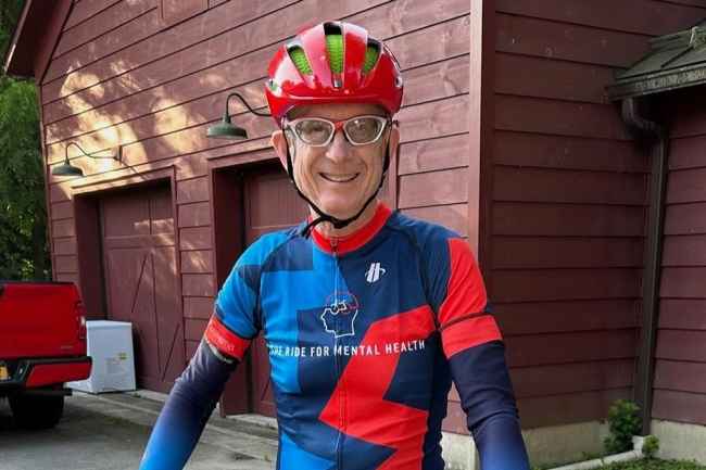 Person in red and blue bike riding gear outside reddish garage