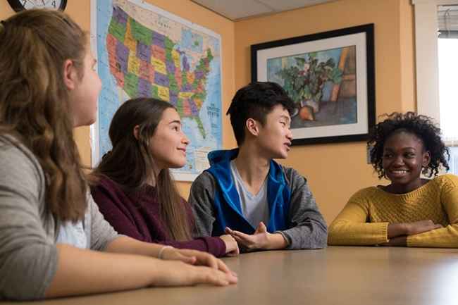 Teens sit at classroom table