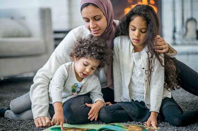 Adult hugging and reading to two children