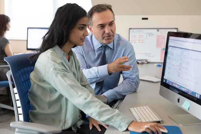 Clinician-researcher works with younger researcher looking at computer