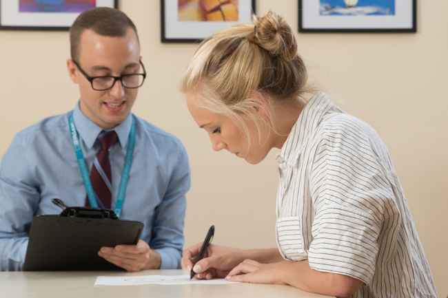 Clinician with clipboard helps patient take a test