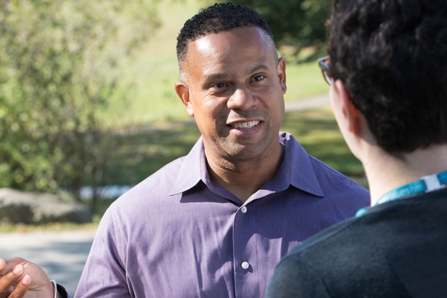Man in light purple shirt outside talks to someone