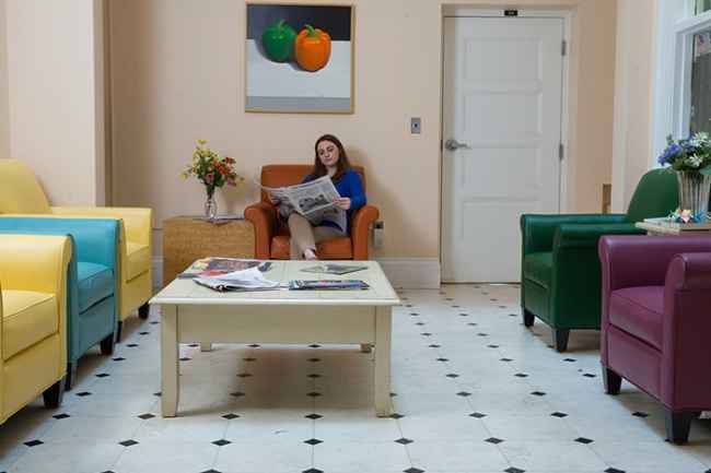 Young woman reads newspaper in colorful sitting room