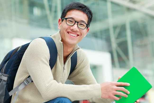 Individual smiling with a backpack and a notebook