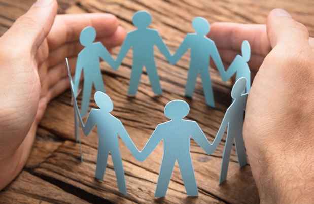 Hands encircle a ring of blue paperdolls