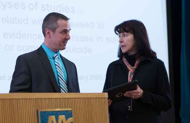 Man and woman discuss near lectern