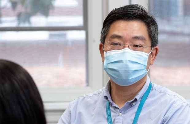 Man in mask talks to another person