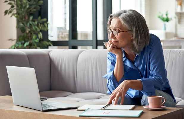 Woman on couch watches laptop screen