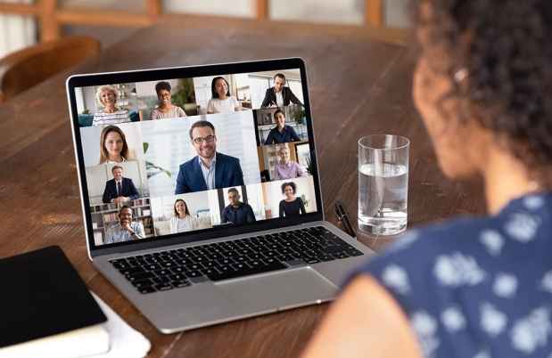 Woman looks at virtual meeting on laptop screen