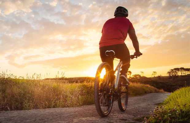 Riding bike on rural road into sunset