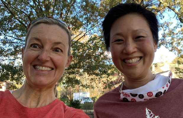 Two women pose for post run selfie by trees