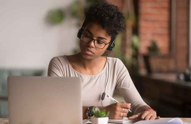 Young woman watches webinar taking notes