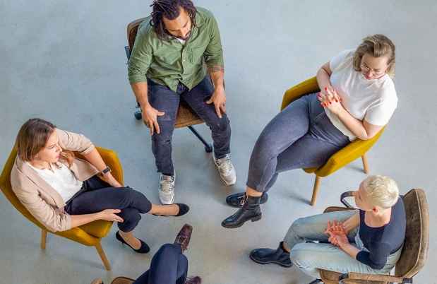 people in chairs talking in group therapy