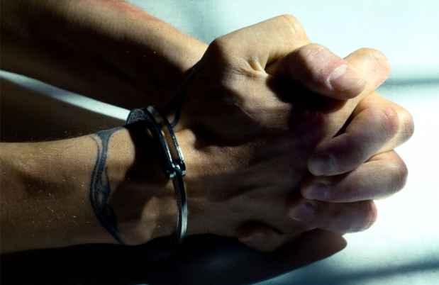 Hands in handcuffs resting on a table