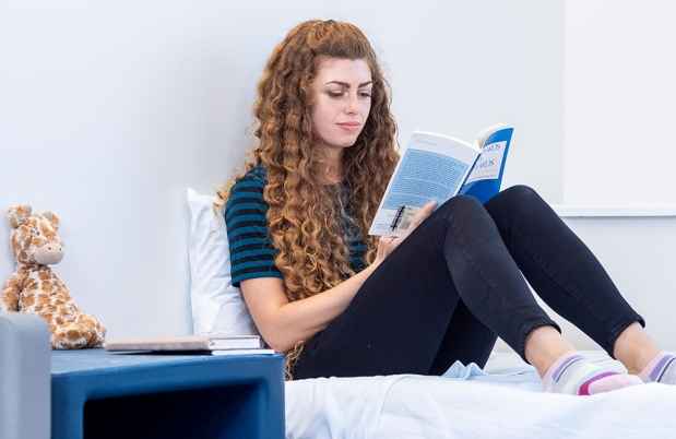 Young woman reads sitting on bed