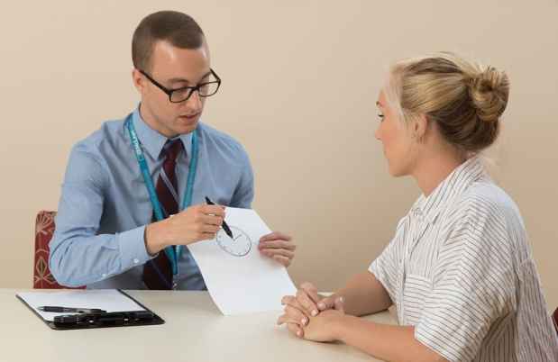 A clinician shows a patient how to take a neuropsychological test
