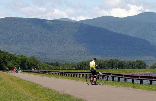 Bicyclists on a road toward mountains and blue cloudy skies